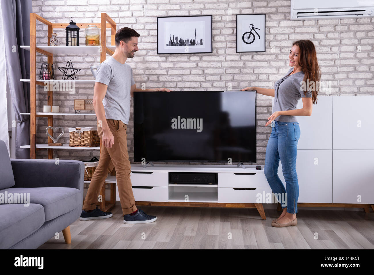 Seitenansicht des jungen Paares Anheben Fernsehen zu Hause Stockfoto