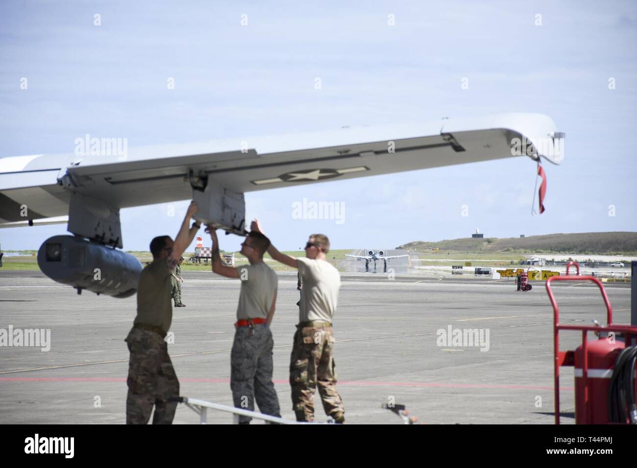 Eine A-10 Thunderbolt II Angriff Flugzeug an die 442 d Fighter Wing zugeordnet Taxis in Richtung Parking während Flieger ein Waffen prüfen Pylon auf ein anderes Luftfahrzeug Feb.21, 2019, bei der Marine Corps Base Hawaii. Die charakteristische Markierungen auf der Flugzeuge im Vordergrund commemmorate den 6. Juni 1944, die Invasion in der Normandie, in der die 442 d Troop Carrier Group eine Rolle gespielt. Stockfoto