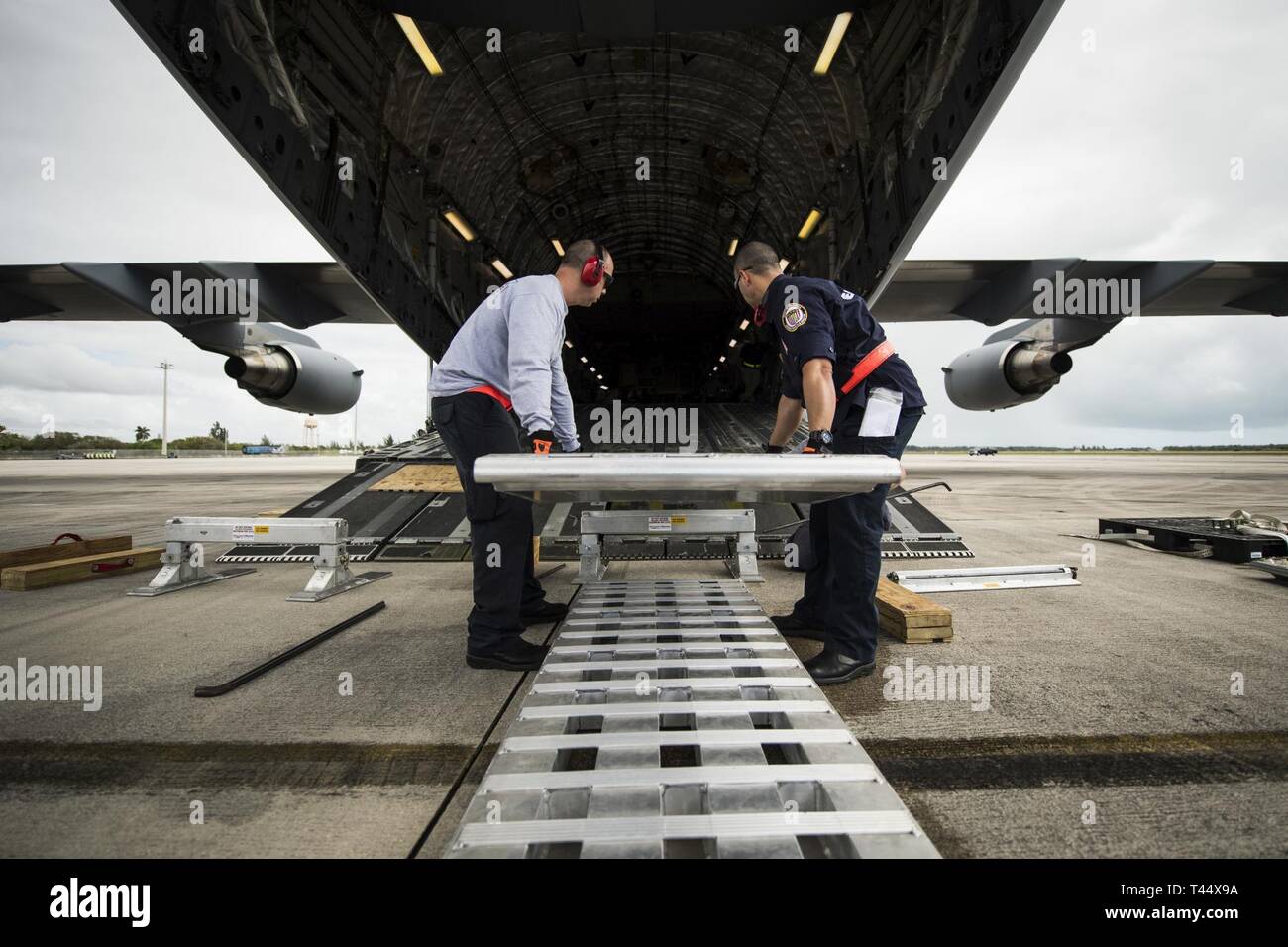 Mitglieder des Südflorida Urban Such- und Rettungsteam, installieren Sie die Rampen auf die C-17 Globemaster III, zum Hochladen von Fahrzeugen während der Übung Patriot Sands, Homestead Air Reserve Base, Fla., Nov. 23, 2019. Übung Patriot Sands ist ein gemeinsamer Service von der Air Force Reserve, die Ersthelfer des Bundes, der Länder, der Staat, die lokalen Agenturen zu integrieren und das Militär durch die Bereitstellung eines schnellen Antwort Ausbildung im Falle eines regionalen Notfall oder Naturkatastrophe koordiniert. Stockfoto