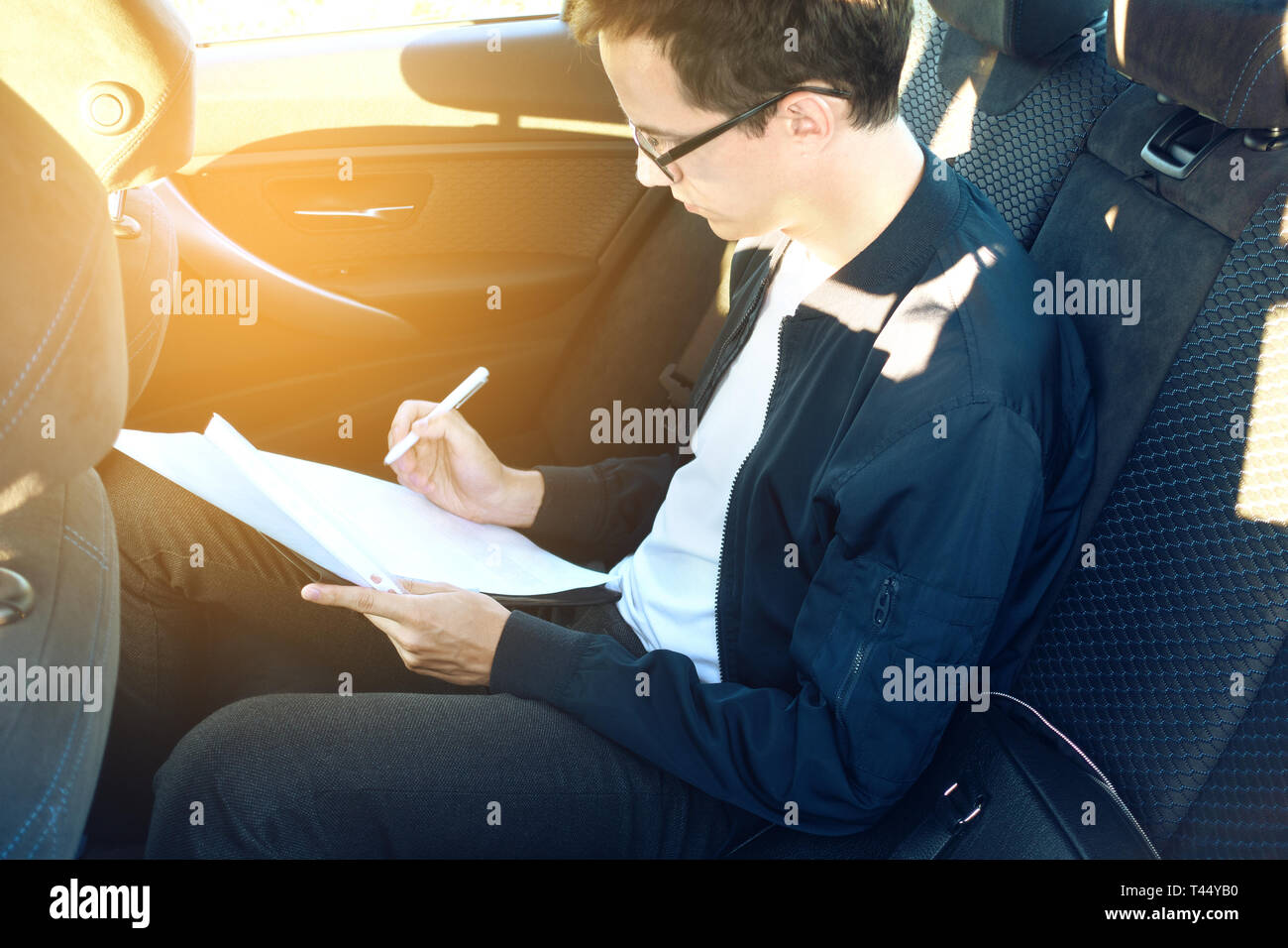 Jungen Kerl Geschäftsmann in Gläser Dokumente signiert auf dem Rücksitz im Auto sitzen. getönt Stockfoto