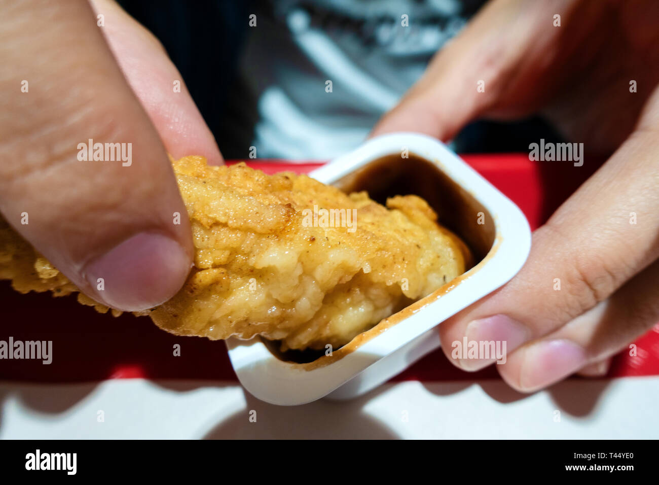 Man Hände Huhn in Teig Dunks in Sauce zu essen Stockfoto