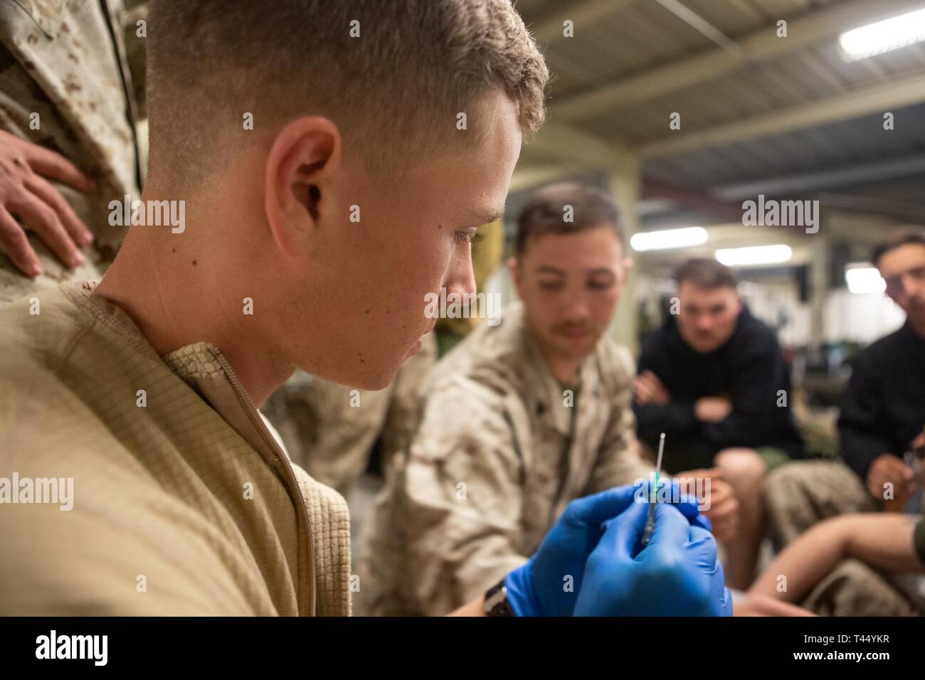 Us Marine Corps Lance Cpl. Ryan Davis prüft eine Nadel, bevor sie mit einer IV-Ausbildung an der National Training Center, Fort Irwin, Calif., 24.02.2019. Us-Marines mit 5 Air Naval Geschützfeuer Liaison Firma, III Marine Expeditionary Force Information Group und Japan Masse Verteidigung-kraft Soldaten mit 11 Infanterie praktiziert, IVs einander ihre medizinischen Skillset zu verbessern. Davis, ein Eingeborener von Wichita, Kansas, ist ein Funker mit 1St Brigade, 5 ANGLICO. Stockfoto