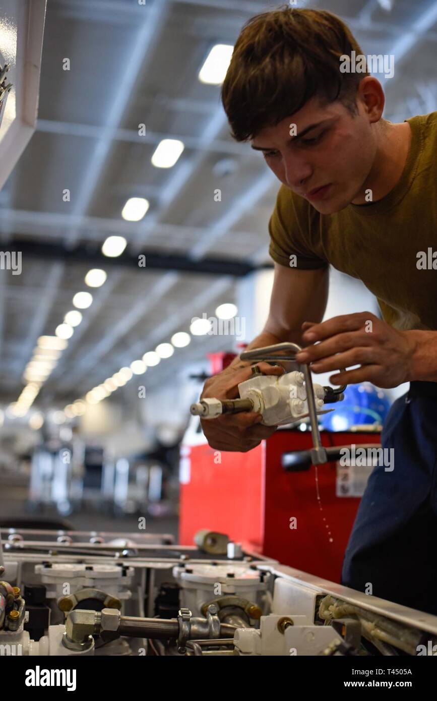 Pazifik (Feb. 25, 2019) Aviation Support Equipment Techniker 3. Klasse Christopher Petty, aus San Antonio, Texas, entfernt ein Zylinder aus einem Spotting dolly im Hangar Bucht der Flugzeugträger USS Theodore Roosevelt (CVN 71). Theodore Roosevelt ist die Durchführung von Routineaufgaben im östlichen Pazifik. Stockfoto