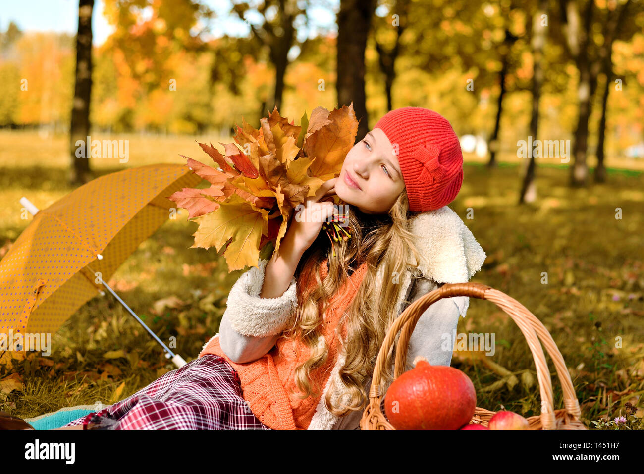 Nachdenklicher Teenager. Herbst Romantik Portrait einer schönen jungen Mädchen in einem Red hat. Im Hintergrund steht ein Korb mit Äpfeln und einen Kürbis, ein Schrei Stockfoto