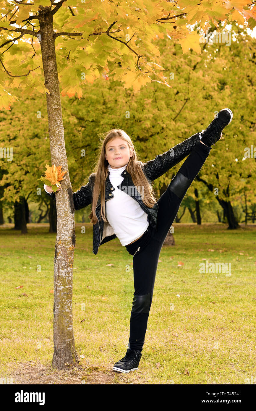 Herbst portrait von wenig gymnast Mädchen. Kind zeigt Stretching im Park in der Natur Stockfoto