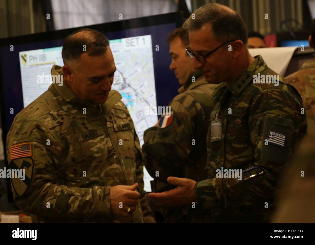 Generalmajor Paul Calvert (links), der kommandierende General der Kavallerie Division 1 stellt Informationen aus der griechischen Armee Oberstleutnant Smyrna Panagiotis, während der übung Dynamische Front 19, am 4. März Grafenwöhr Training Area, Deutschland. Dynamische Vordere 19 ist eine multinationale Übung der US-Armee in Europa zur Verbesserung der Alliierten und Partner nation Fähigkeit zu lange liefern - Bereich Feuer. Es ermöglicht Verbündeten persönlich, fachlich, technisch und taktisch stärker und fähiger Kräfte in der Zeit der Krise zu schaffen. Stockfoto