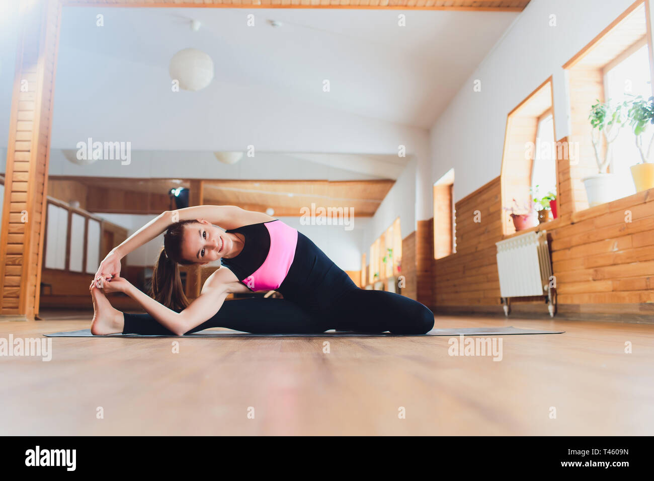Eine junge Frau, die Yoga - Asanas in der Halle. Eka Pada shirshasana. Pavirittu Jana Shirshasana. Stockfoto