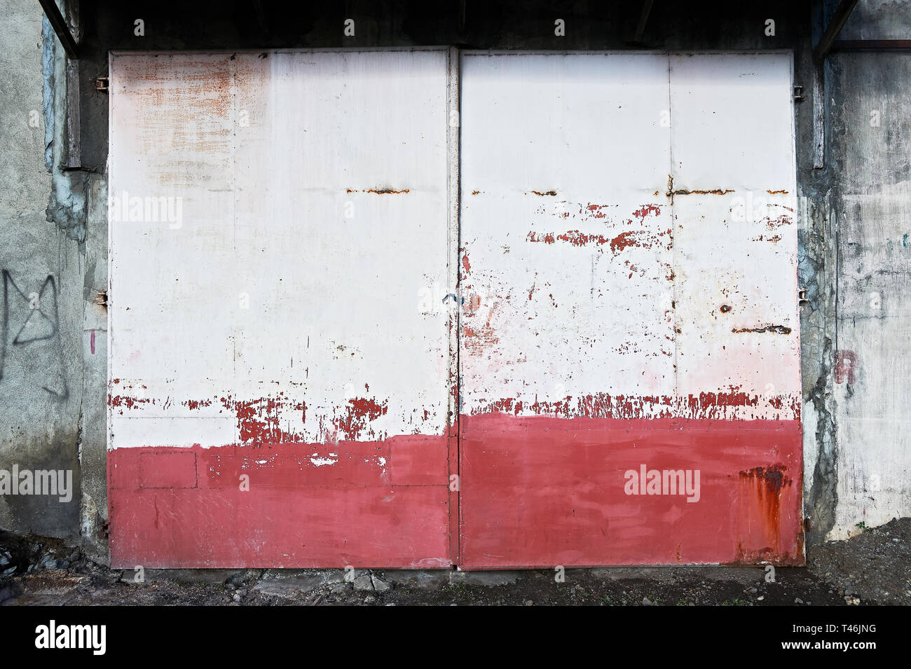Rote und weiße alten rostigen Eingang Metal Gate dargestellt in Iloilo City, Philippinen, tagsüber. Hinter dem Tor ist ein industrieller Unternehmen. Stockfoto