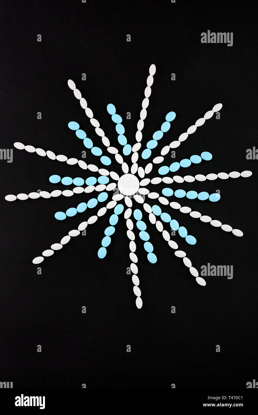Schneeflocke aus weißen und blauen Pillen auf schwarzem Hintergrund. Stockfoto