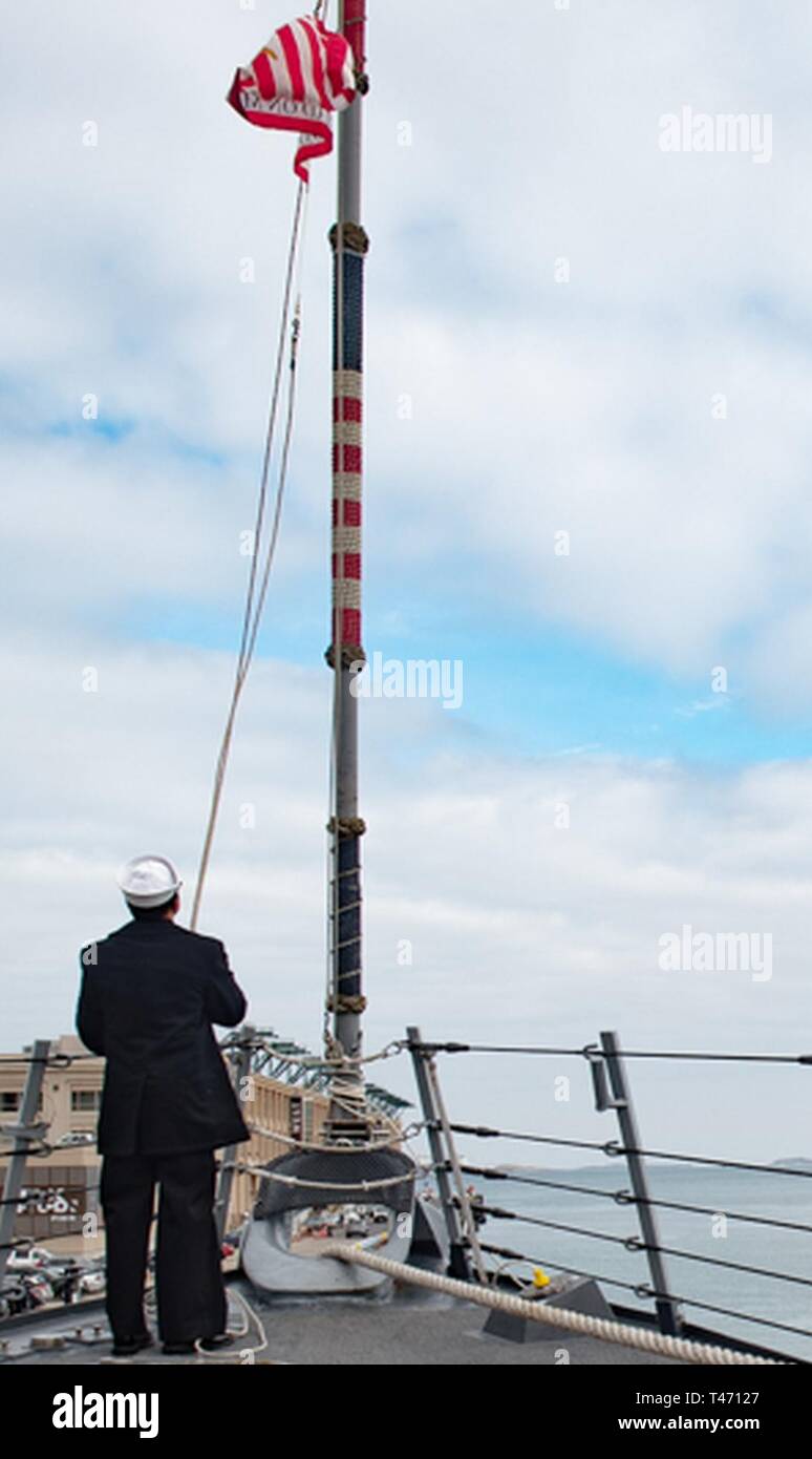 BOSTON (Mar. 14, 2019) das Schiff Veteran 2. Klasse Marquise Ball, ein Eingeborener von Norfolk, Virginia, Hebezeuge der Marine Jack an Bord der Arleigh-Burke-Klasse Rakete Zerstörer USS Jason Dunham (DDG109). Dunham ist in Boston in der Stadt St. Patrick's Day Veranstaltungen teilzunehmen. Stockfoto