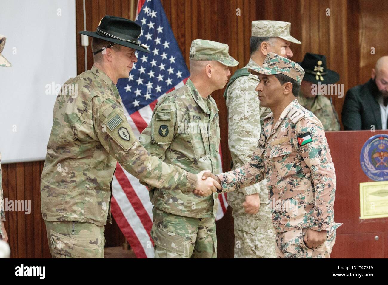 Us-Armee Oberstleutnant Jeremy T. Hopkins, 1.Staffel, 18 Cavalry Regiment, Commander, Brig. Gen. Michael D. Wickman, stellvertretender kommandierender General-Manöver, 34th Infantry Division, Jordan und Jordan Streitkräfte Brig. Gen. Khalid Mohammed Al-Masaeid, Region Nord Commander, gratulieren Firma Kommandanten im 10 Bundesgrenzschutz Kraft Bataillon (BGF) bei der Abschlussfeier der Peace Operations Training Center in der Nähe von Amman, Jordanien, 14. März 2019. Staffelung der JAF Soldaten aus der gemeinsamen operationellen Engagement Programm bedeutete die Fertigstellung eines 10-wöchigen Trainingsprogramm wi Stockfoto