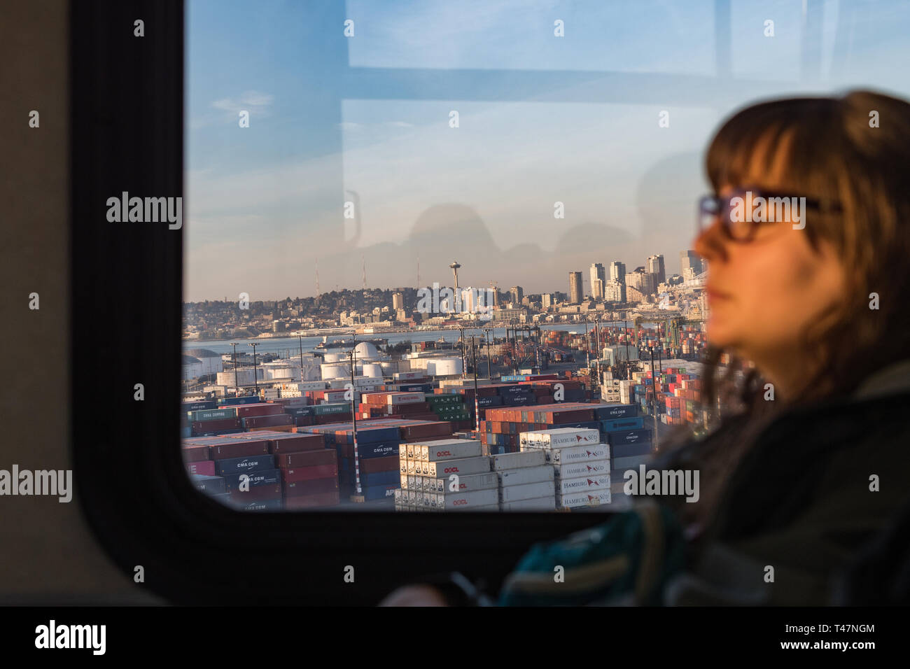 Blick auf Seattle Bucht und bei großen Gebäuden bei Sonnenuntergang aus dem Fenster einer öffentlichen Bus in dem eine junge Frau ruht. Stockfoto