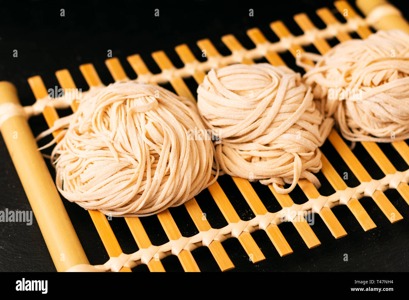 Asiatische Lebensmittel Konzept hausgemachte uncook orientalische Eiernudeln auf Bambus tablett mit Kopie Raum Stockfoto