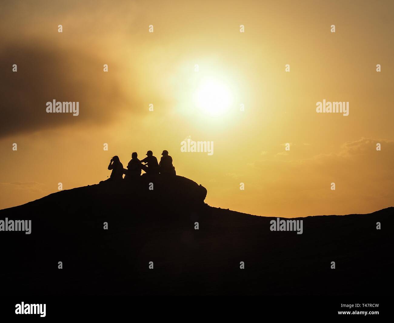 Silhouetten, Touristen sitzen auf den Felsen bei Sonnenuntergang, Dascht-e Lut, Wüste Lut, Iran Stockfoto