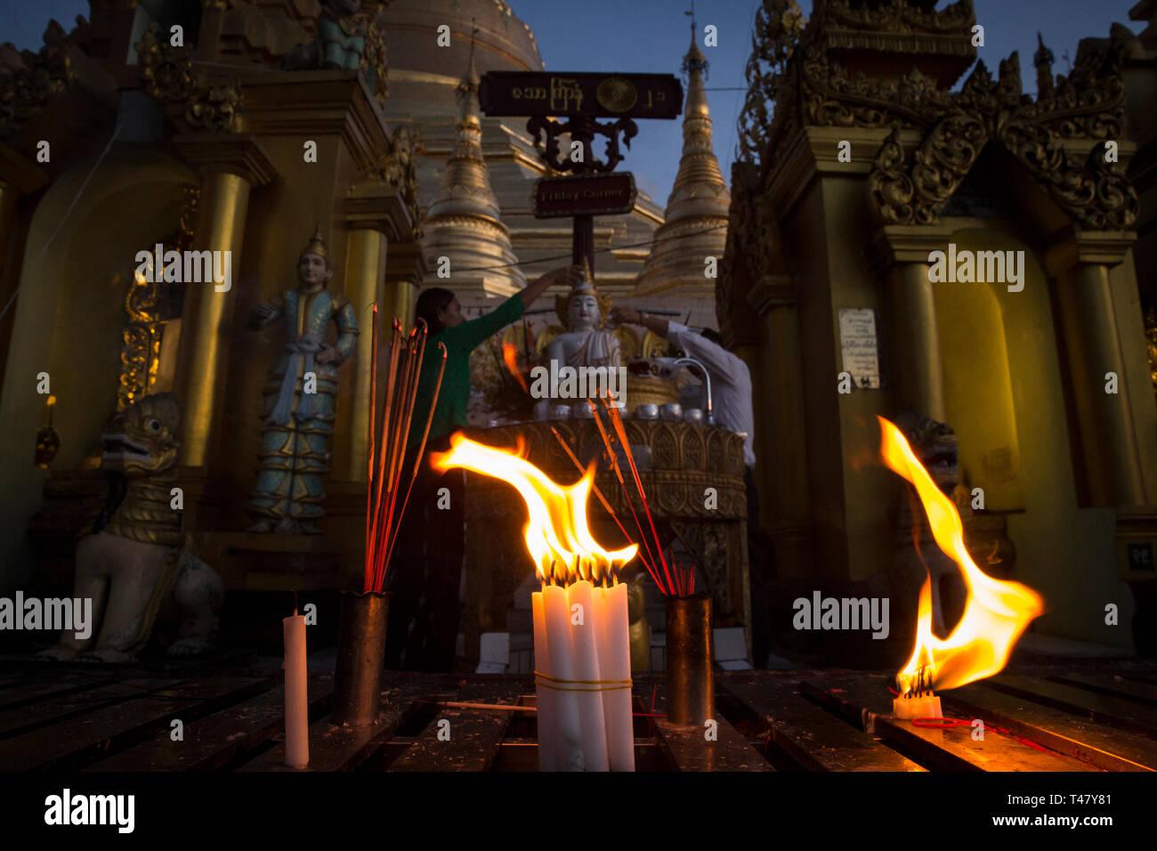 Yangon, Myanmar - 19. September 2016: Kerzen brennen, während die Leute Baden eine Statue des Buddha auf der Shwedagon Pagona Stockfoto