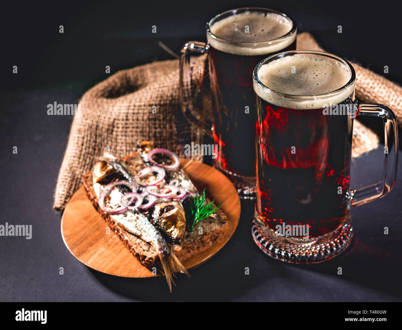 Red Handwerk Bier, heiß geräucherter Fisch Sandwich auf einem dunklen Hintergrund. Low Key Beleuchtung. Stockfoto