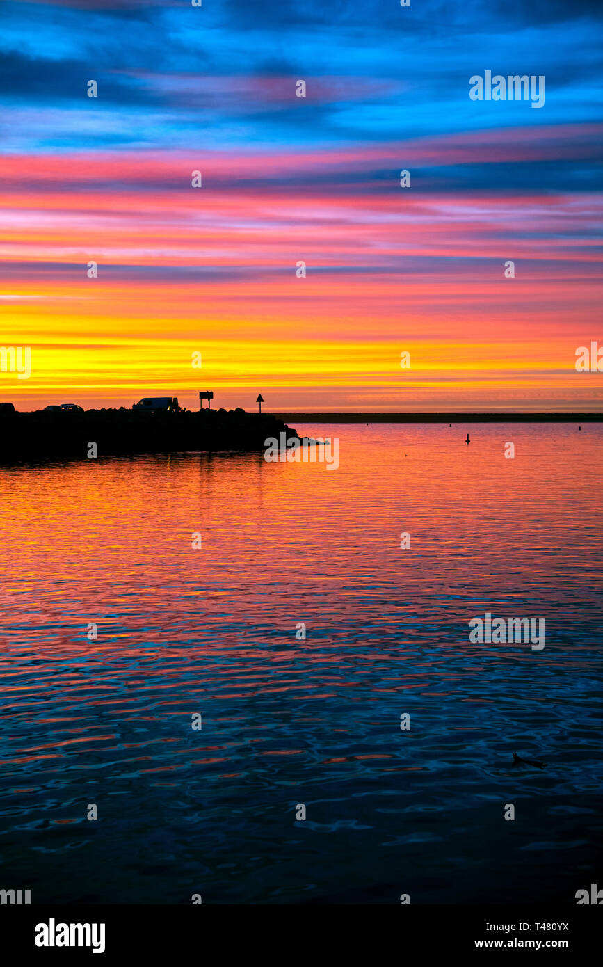 Sonnenuntergang über der Hafeneinfahrt mit Blick auf das Meer, die bunten Himmel. Blue Sky in Rot, Orange und Gelb. Stockfoto