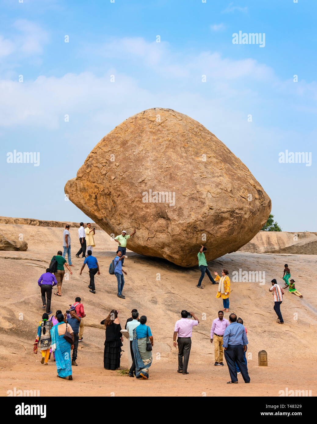 Vertikale Ansicht von Touristen vorgibt, Krishnas Butterball in Mahabalipuram, Indien zu halten. Stockfoto