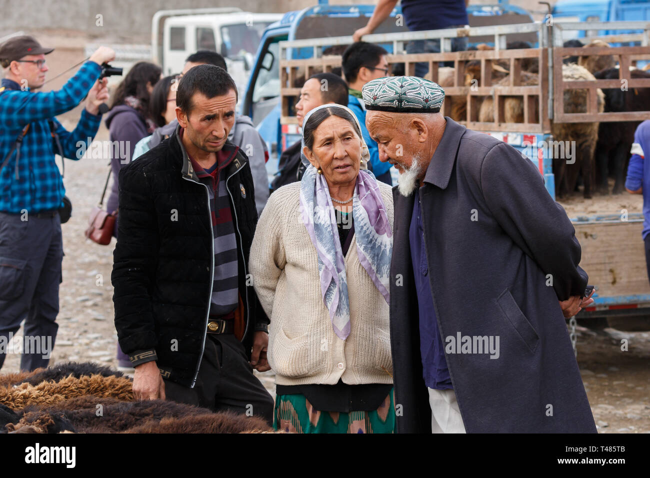 Gespräch zwischen einer älteren Frau und einem Älteren, bärtigen Mann trägt einen doppa am Kashgar Tiermarkt (Provinz Xinjiang, China) Stockfoto