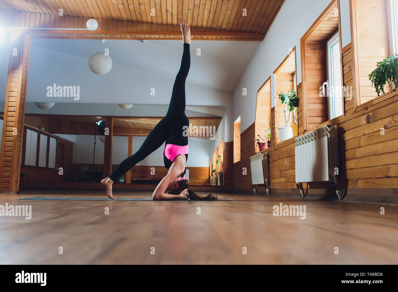 Junge Yogi attraktive Frau yoga Konzept, in salamba sirsasana Übung stehend, Kopfstand darstellen, Arbeiten, Sportkleidung tragen, schwarz Stockfoto