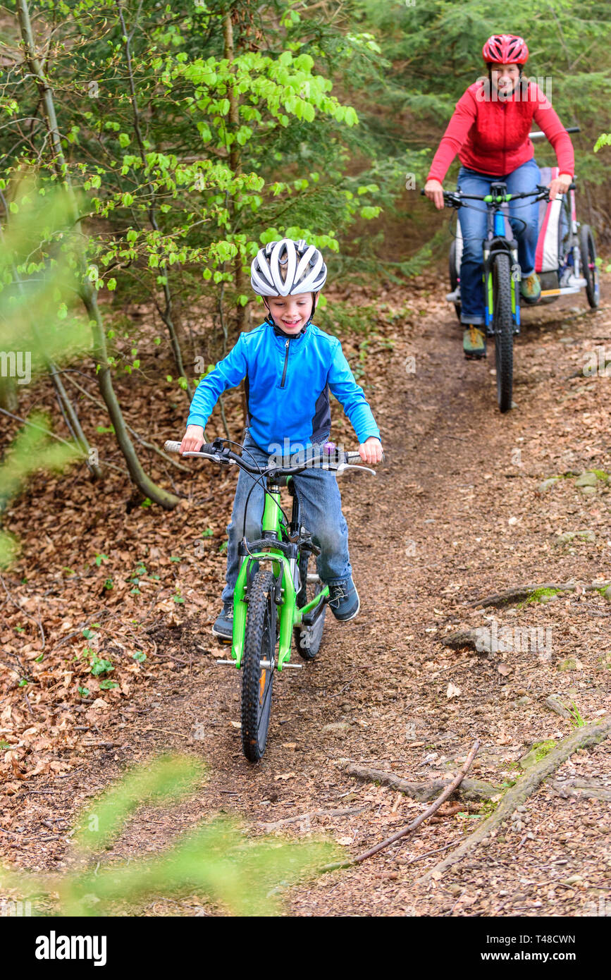 Motiviert junge Radfahren auf Forstweg durch Mutter Stockfoto