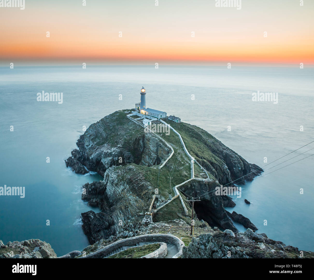 Am frühen Abend Sonnenuntergang Szene mit Blick aufs Meer in Richtung South Stack Lighthouse, Anglesey, Nordwales. Stockfoto