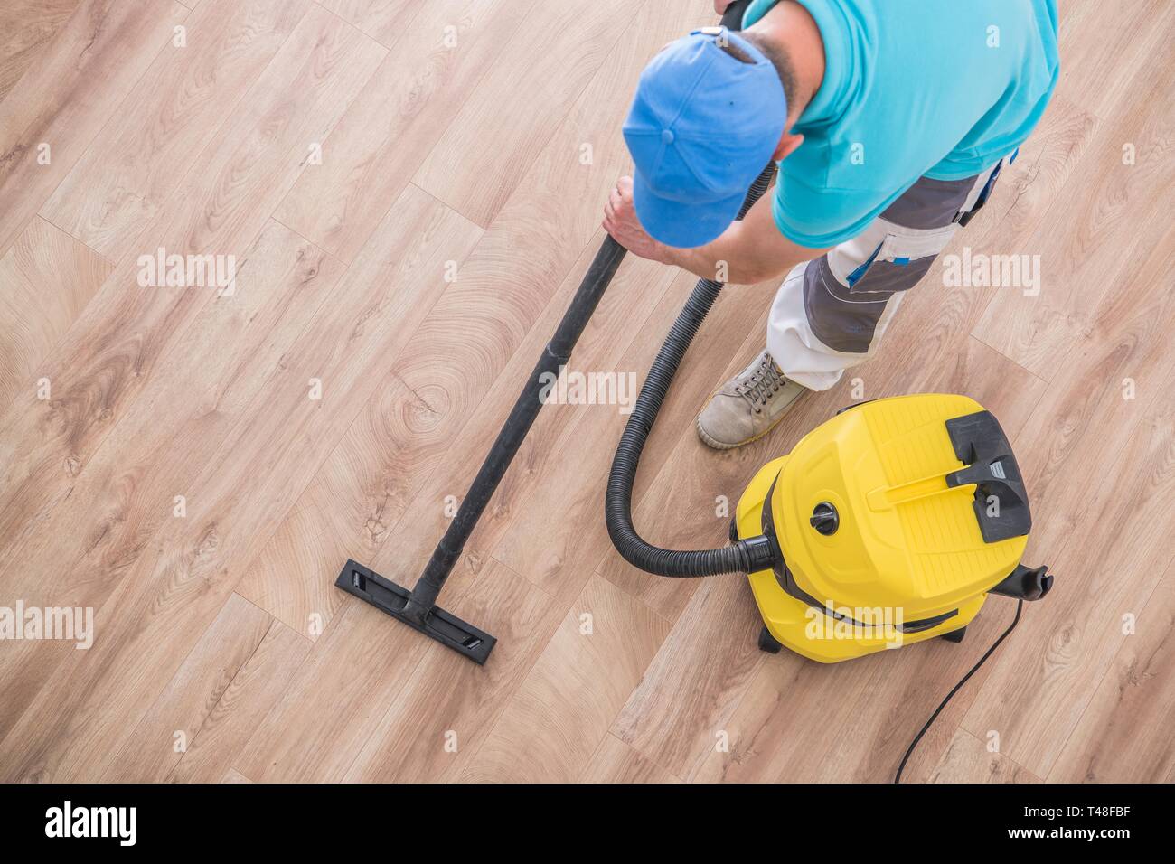 Kaukasische Männer saugen Apartment neuen Parkettboden. Home Reinigung Zeit. Stockfoto
