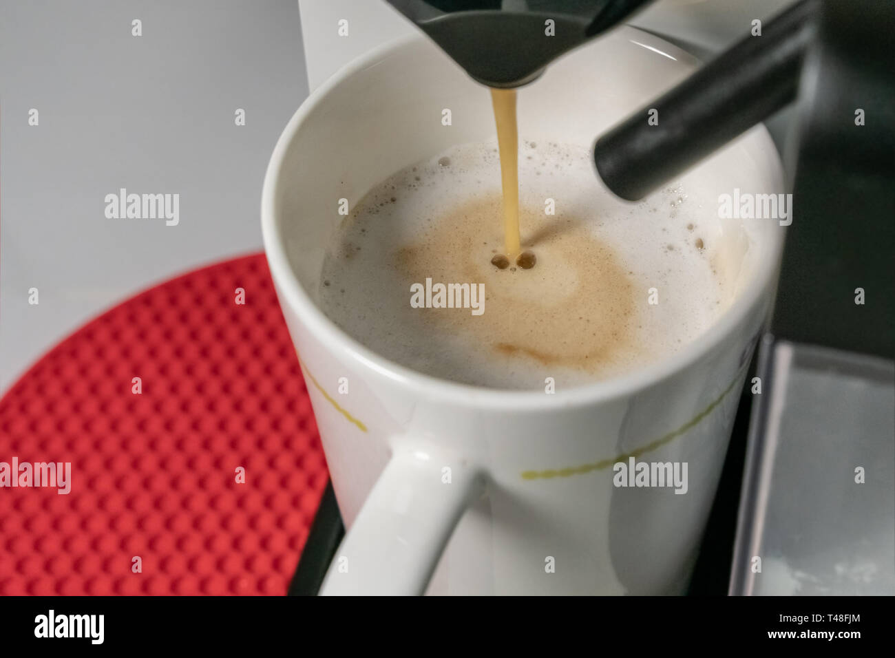 Die Cappuccino - Nahaufnahme von espresso Gießen aus der Kaffeemaschine. Cuppuccino hat die wichtigsten Bestandteile sind Espresso und Milch. Verschwommen Stockfoto