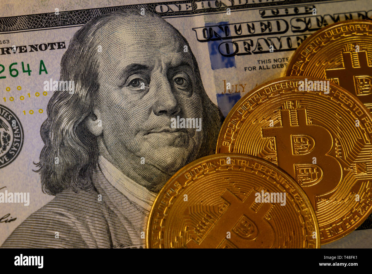 Drei gold- bit-Münzen auf hundert Dollar Banknote auf schwarzen Hintergrund isoliert, cryptocurrency Annahme für die Zahlung und Finanzierung Konzept Stockfoto