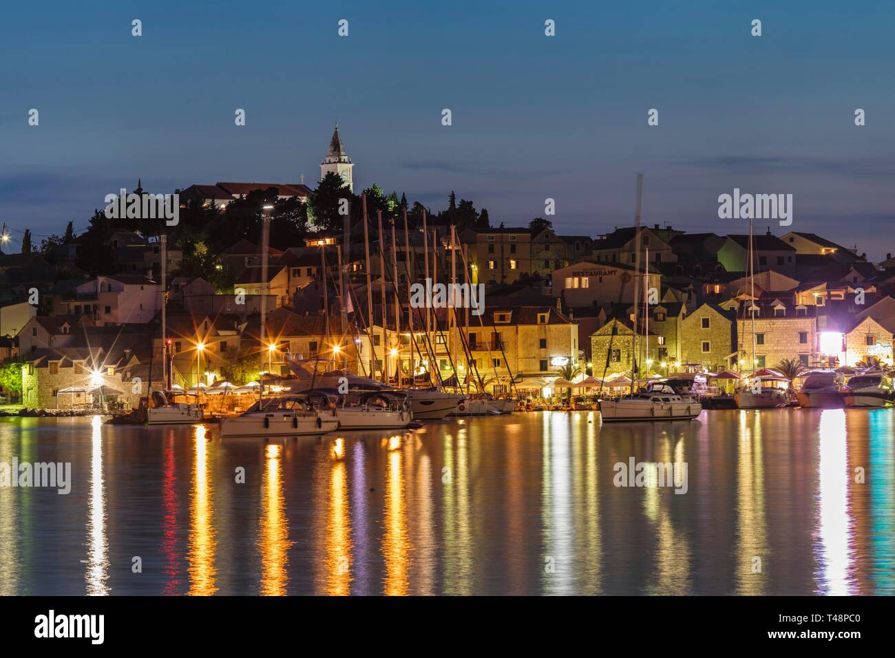 Blick auf die stadt mit Segelbooten und Lichter im Wasser widerspiegelt, Abendstimmung, Primosten, kroatische Adriaküste, Dalmatien, Kroatien Stockfoto
