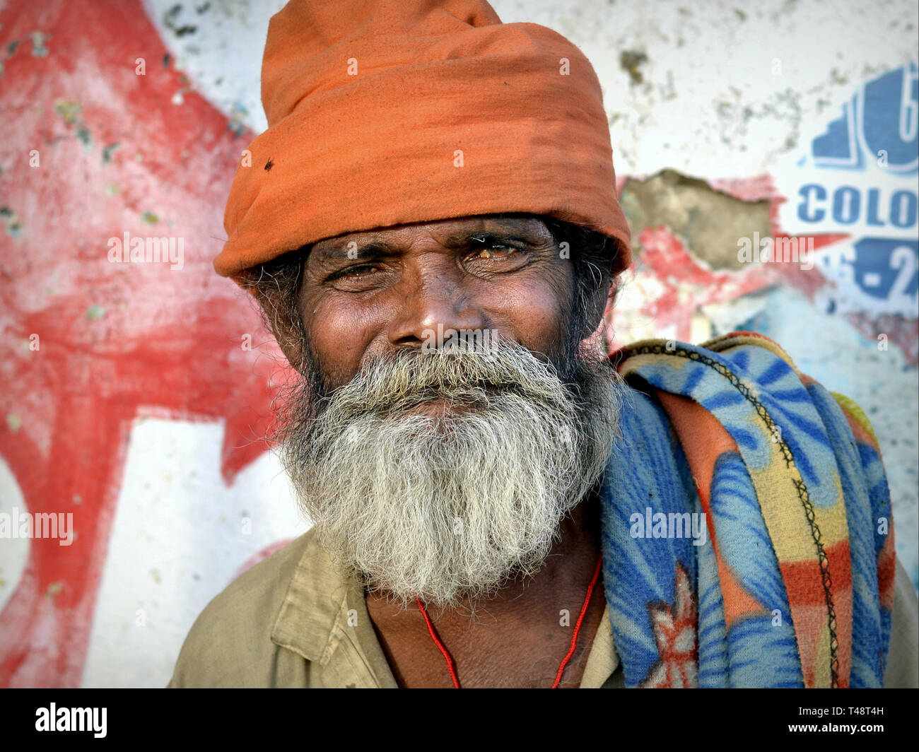 Ältere indische Bettler mit einem schmutzigen orange Turban headwrap posiert für die Kamera. Stockfoto