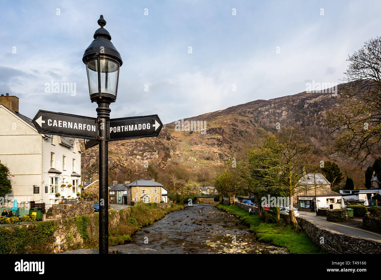 Lampe mit Wegweiser zu porthmadog & Caernarfon am River Bridge in Beddgelert, Wales Am 9. April 2019 Stockfoto