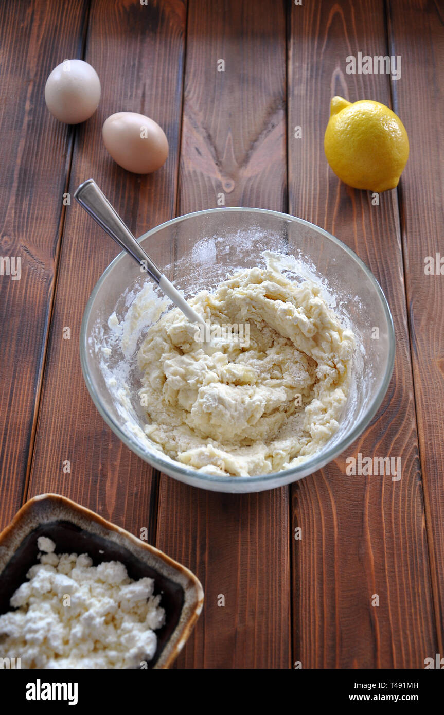 Die hausgemachte Backwaren in der Schüssel mit frischer Zitrone, zwei chiken Eier und Quark auf dem hölzernen Tisch, selektiver Fokus Stockfoto