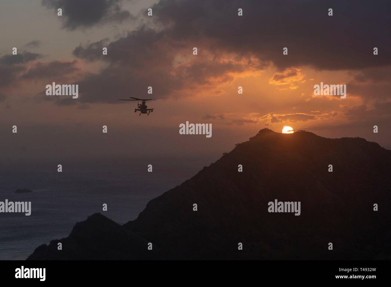 Ein U.S. Marine Corps AH-1Z Viper Kampfhubschrauber mit Marine Light Attack Helicopter Squadron 367 führt ein Denkmal Flug bei Sonnenuntergang April 12, 2019 über Oahu, Hawaii. Der Flug wurde zu Ehren des Marine Viper Piloten Kapitän Brannon und Maj. Matthew M. Wiegand, der in einem Abbruch am 30. März getötet wurden. Stockfoto