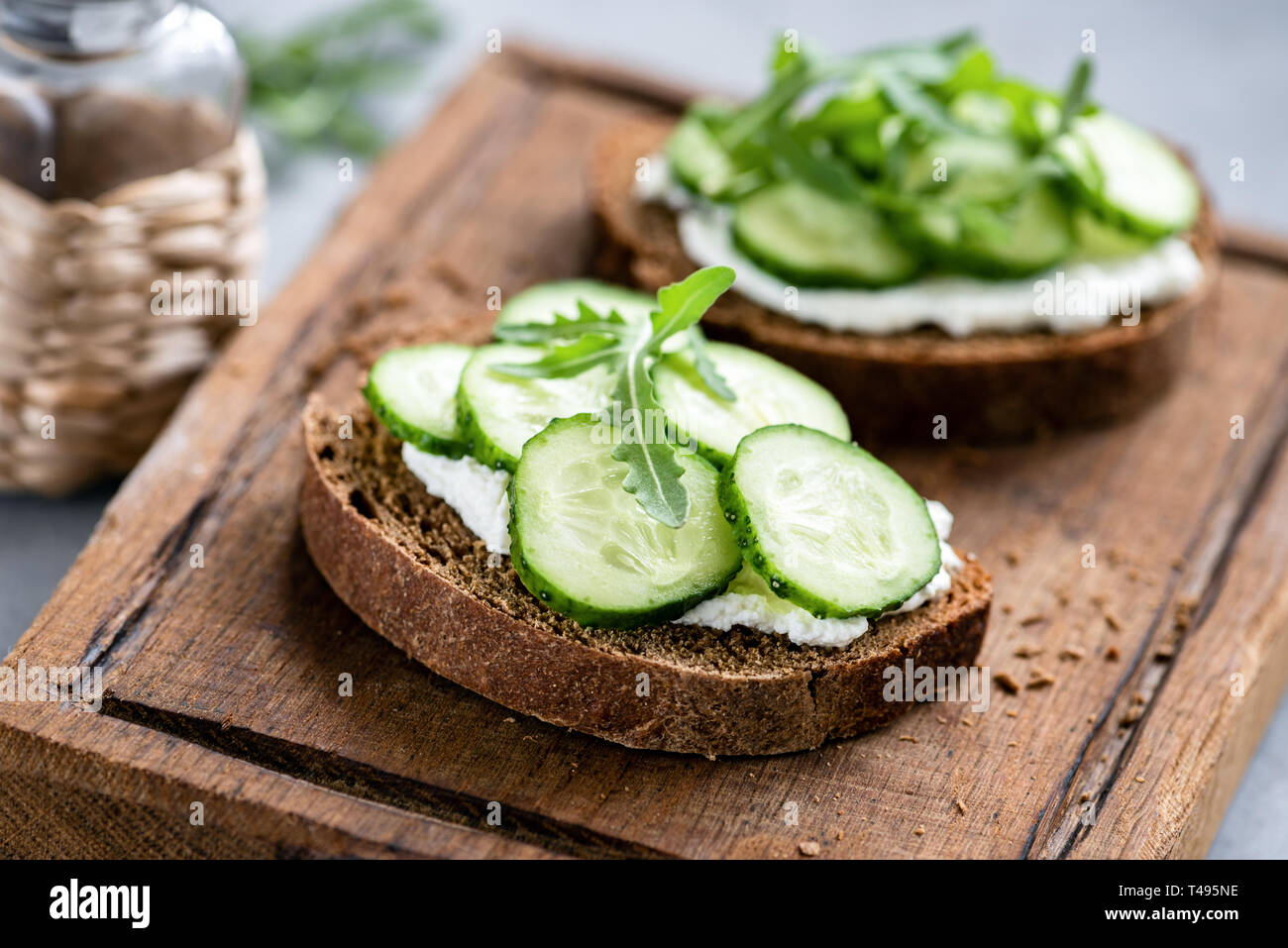 Roggen Brot mit Frischkäse und Gurke auf Holz Schneidebrett ...
