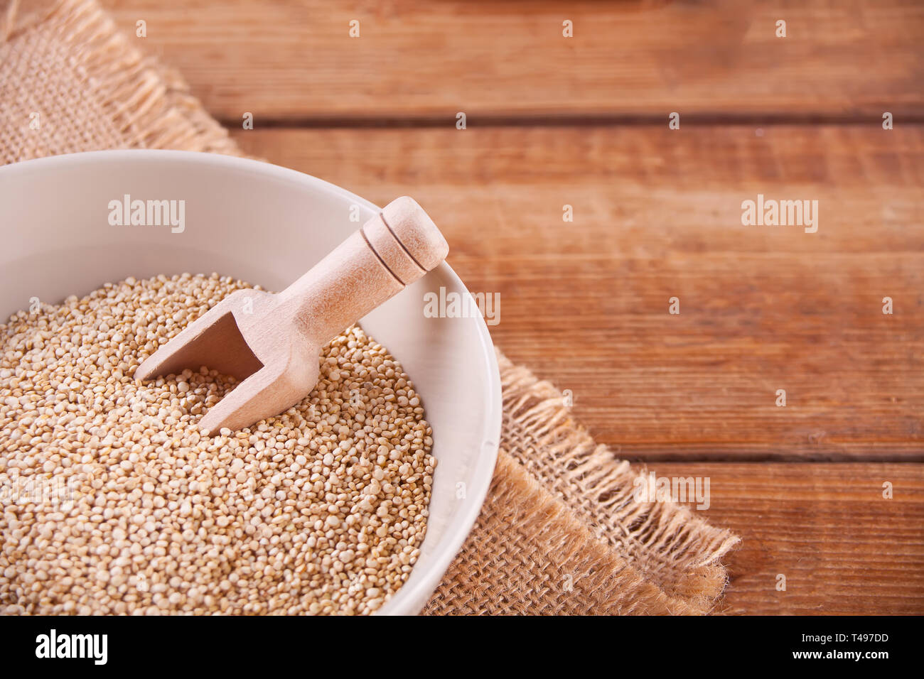 Trockene Quinoa in einer Schüssel mit Holz- Schaufel auf den Holztisch. Ansicht von oben. Kopieren Sie Platz. Stockfoto