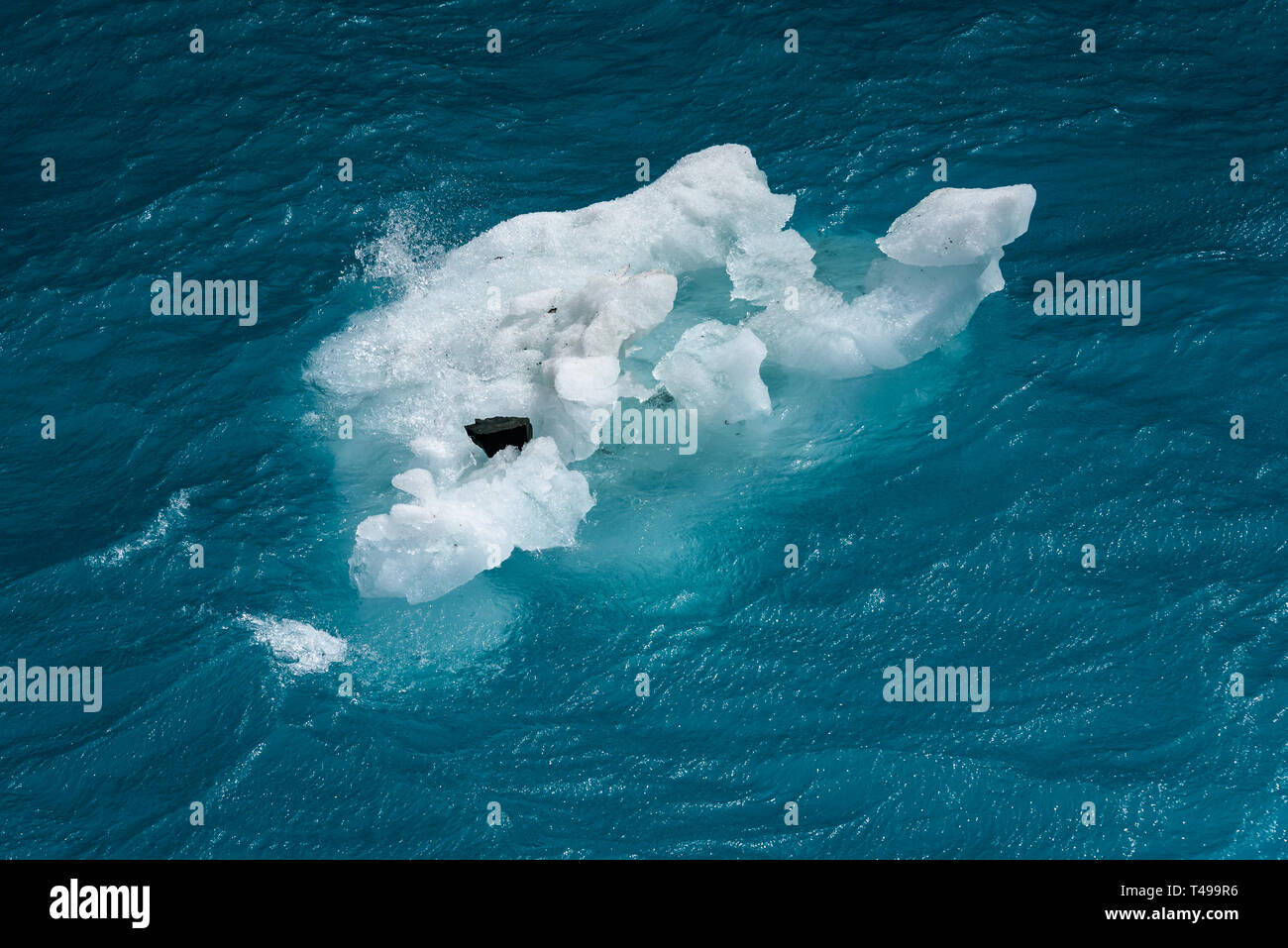 Schönen Meer aquamarinen und Blues mit einem kleinen schwimmenden Eisberg mit einem Rock, als Natur Hintergrund Stockfoto