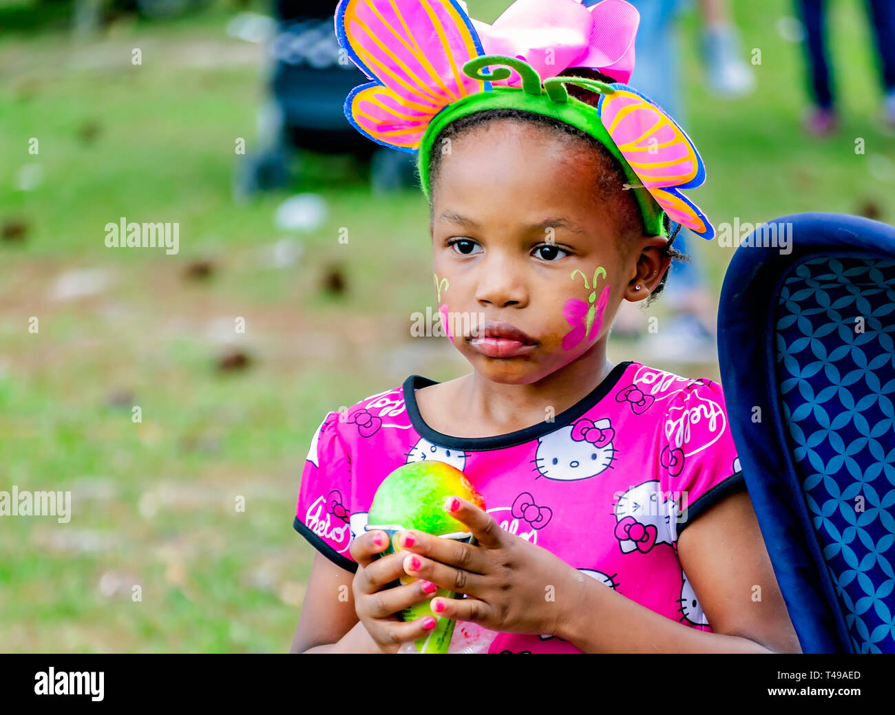 Ein Mädchen im bunny Ohren hält einen regenbogenfarbenen Sno-Kegel während einer Gemeinschaft Ostereiersuche am Langan Park, April 13, 2019 in Mobile, Alabama. Stockfoto