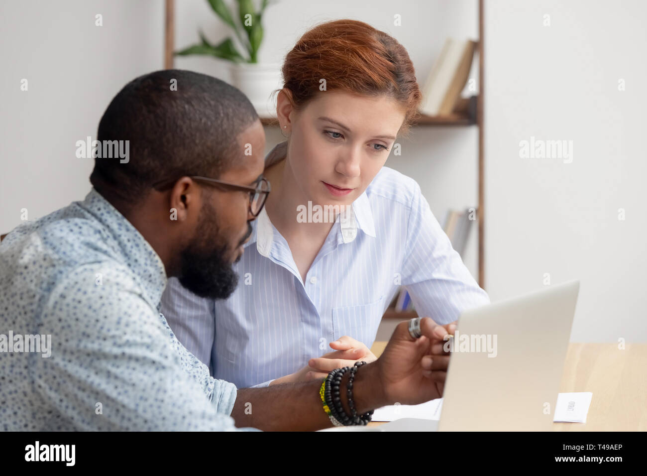 Afrikanische mentor Berater erklären, computer Arbeit mit kaukasischen Praktikantin client Stockfoto