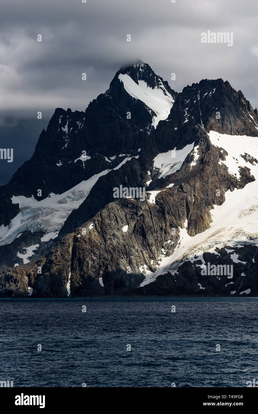 Moody Berg Szene von einem Sonnenstrahl hervorgehoben, mit stürmischen Wolken, blaues Meer und Schnee und Gletscher auf der Insel Berg, Drygalski Fjord Stockfoto