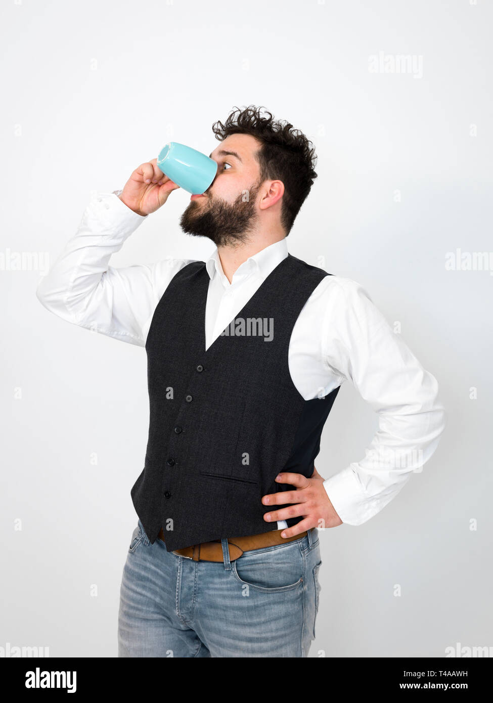Gut aussehender, junger Mann mit schwarzen Bart mit Türkis Tasse Kaffee oder Tee Tasse vor weißem Hintergrund posiert und die verschiedenen Gesichtsausdrücke Stockfoto