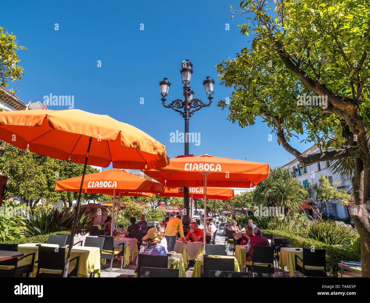 Marbella Orange Square Essen im Freien unter Sonnenschirmen - Plaza de los Naranjos, Speisen im Freien, Menschen, die Essen & Trinken in der Altstadt von Marbella Spanien genießen Stockfoto