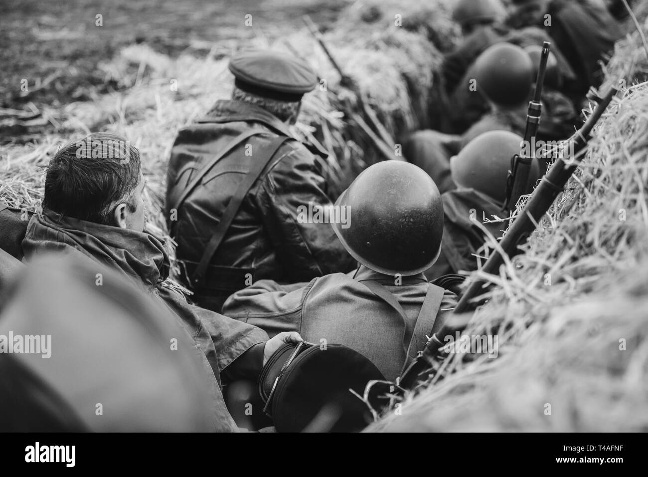 Re-enactors gekleidet als Zweiter Weltkrieg russisch-sowjetischen Soldaten der Roten Armee versteckt im Graben sitzen. Foto in den Farben Schwarz und Weiß. WWII WW2. Stockfoto