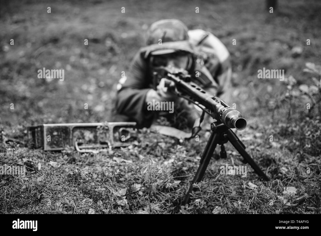 Re-Enactor gekleidet als Zweiter Weltkrieg Deutsche Wehrmacht Soldat ein Maschinengewehr auf gegnerische aus Graben im Wald. Foto in den Farben Schwarz und Weiß. Stockfoto