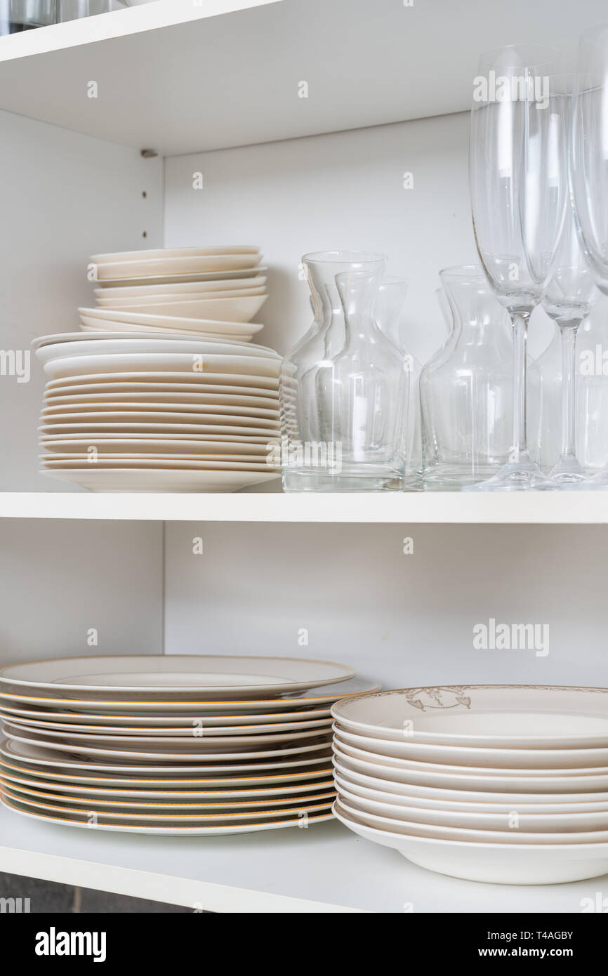 Gläser, Teller und Schüsseln in einem Schrank in der Küche Stockfoto