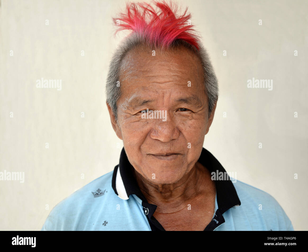 Ältere malaysischen Chinesen mit einem Patch von rosa gefärbte Haare für die Kamera posiert. Stockfoto