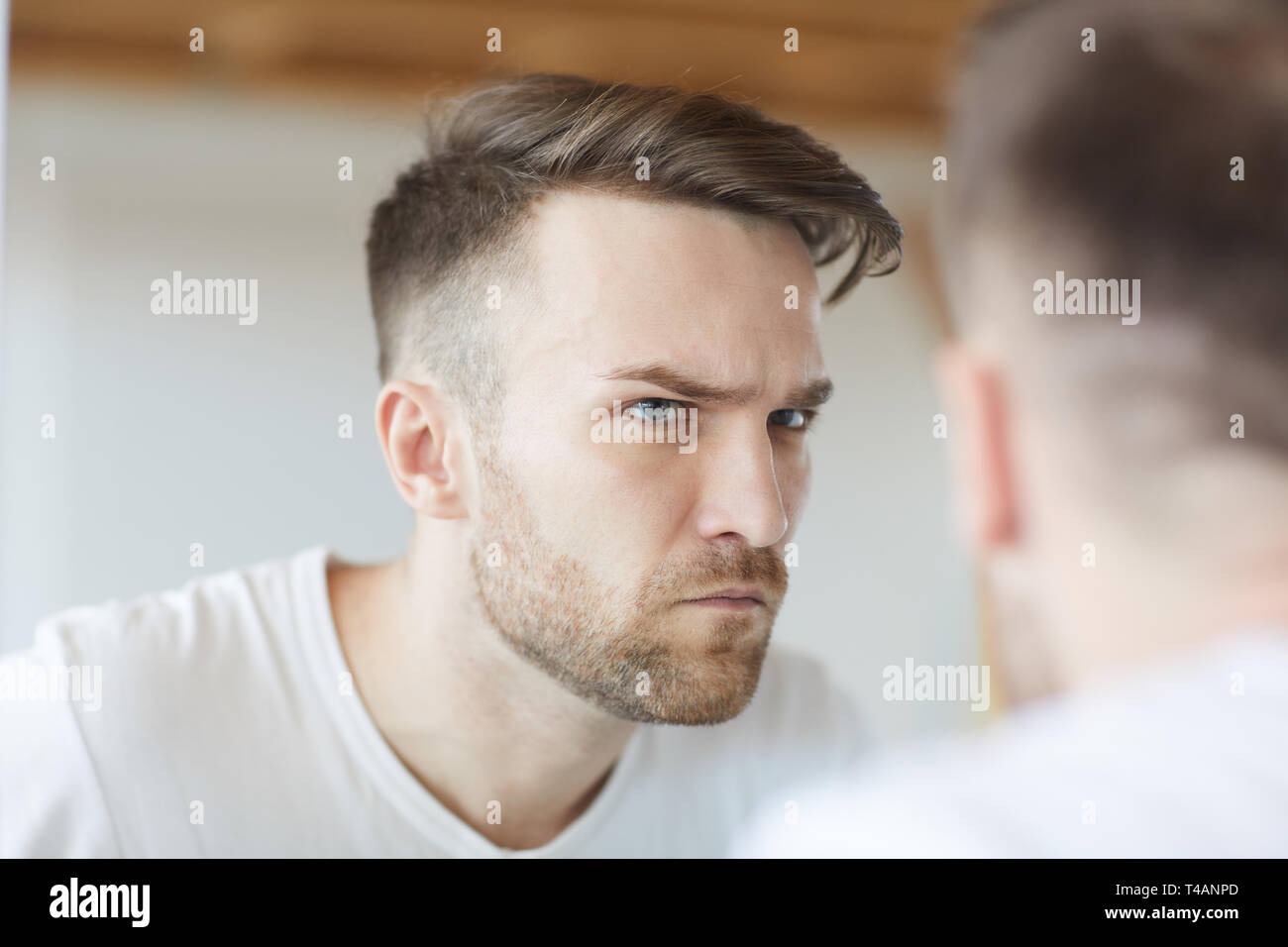 Stirnrunzelnd Mann im Spiegel Stockfoto