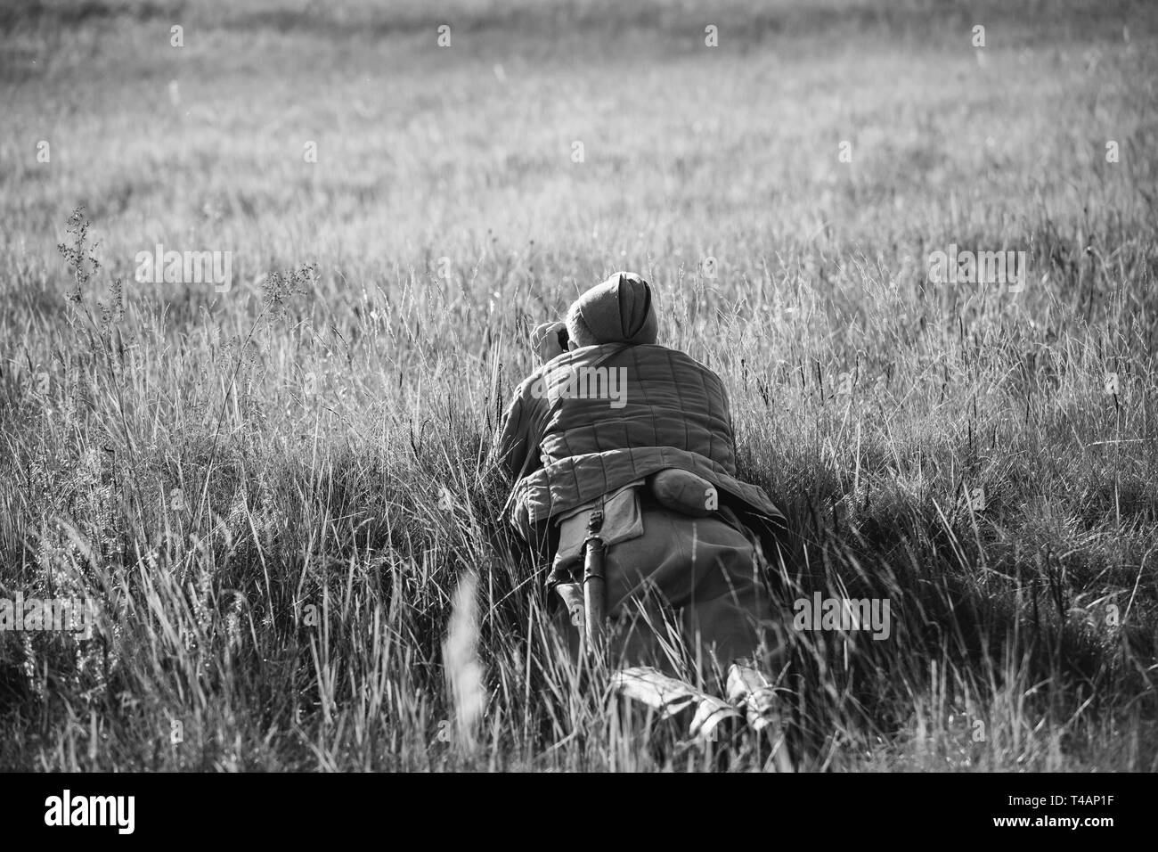 Re-Enactor gekleidet, wie sowjetische Rote Armee Soldat Scout an einem alten Armee Fernglas schaut. WWII WW2 Russian Intelligence Bereich. Foto in Schwarz und Weiß Colo Stockfoto