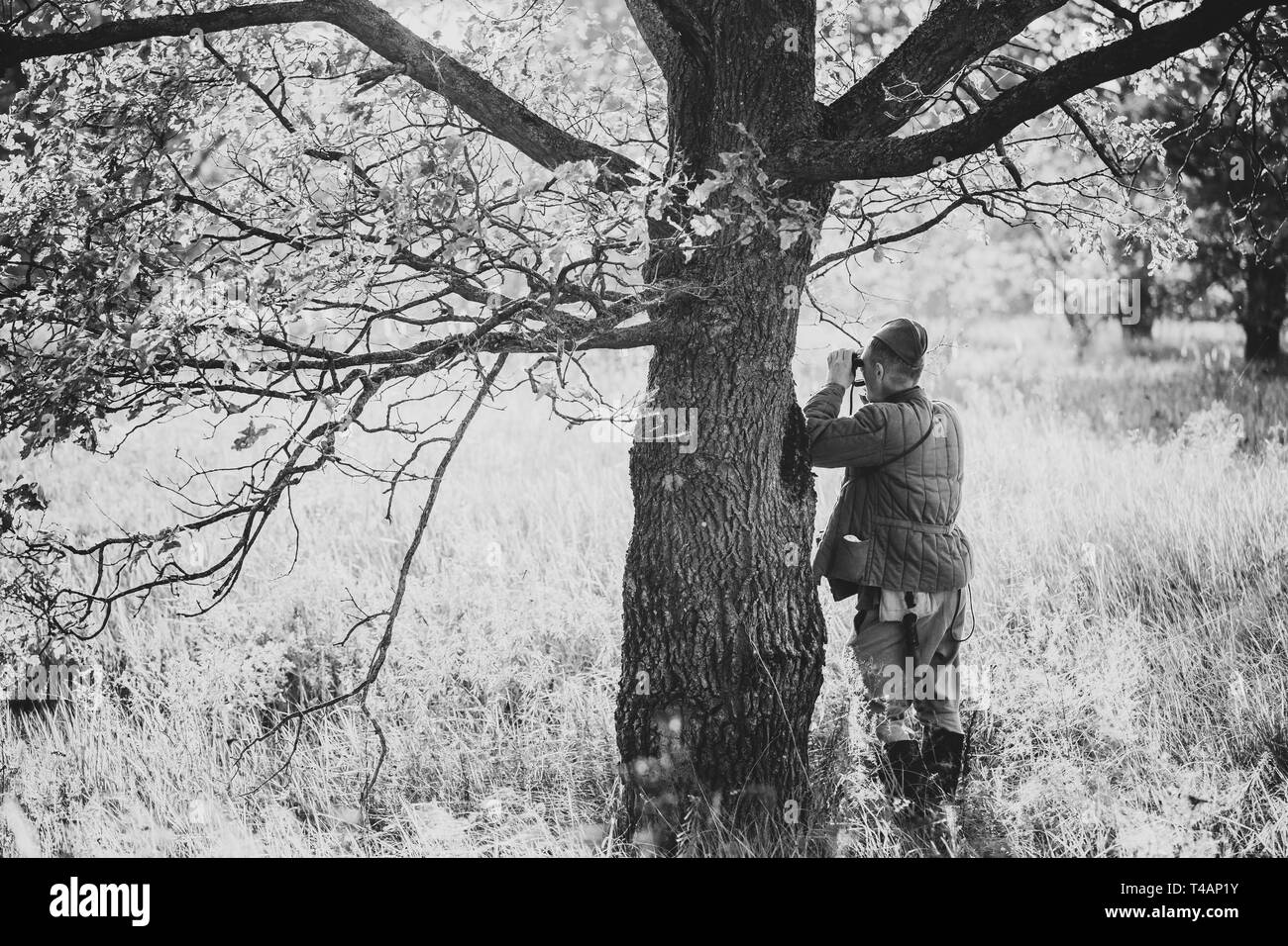 Re-Enactor gekleidet, wie sowjetische Rote Armee Soldat Scout an einem alten Armee Fernglas schaut. WWII WW2 Russian Intelligence Bereich. Foto in Schwarz und Weiß Colo Stockfoto
