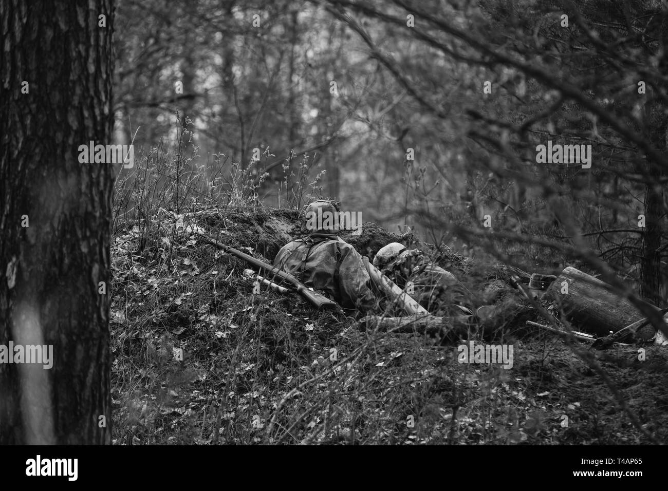 Zwei Re-enactors als Deutsche Wehrmacht Infanterie Soldaten im Zweiten Weltkrieg versteckt Sitzen mit Gewehr Waffe in einen Hinterhalt in Graben in Wald gekleidet. Foto Stockfoto